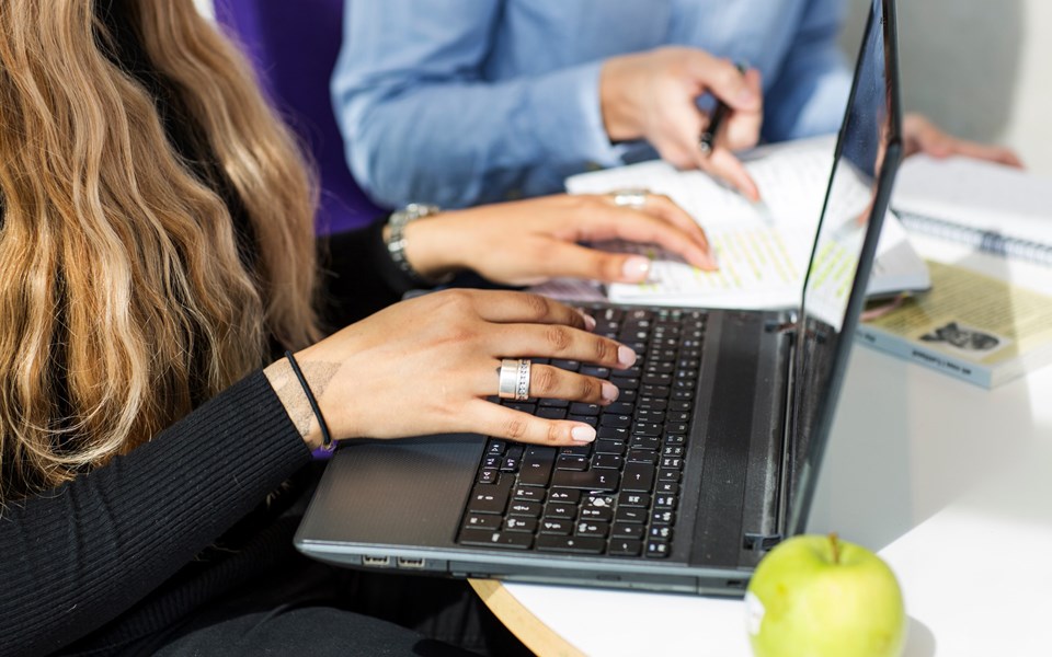 Bilden visar händer och tangentbordet på en laptop.