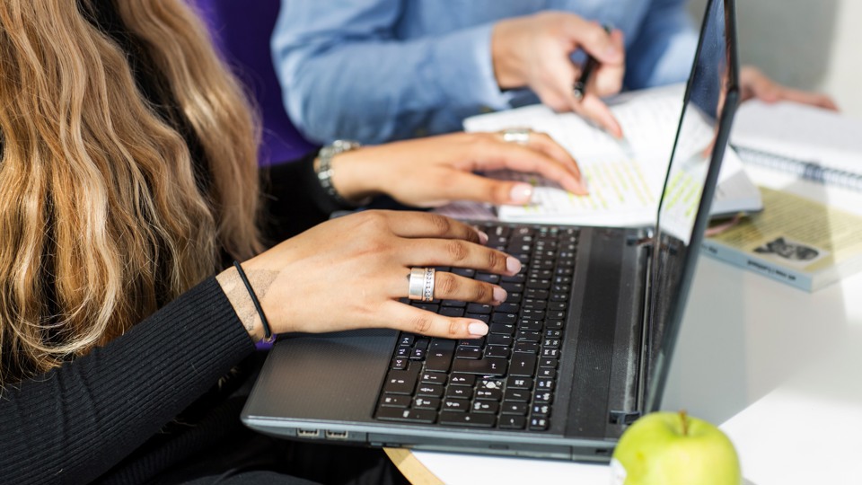 Bilden visar händer och tangentbordet på en laptop.