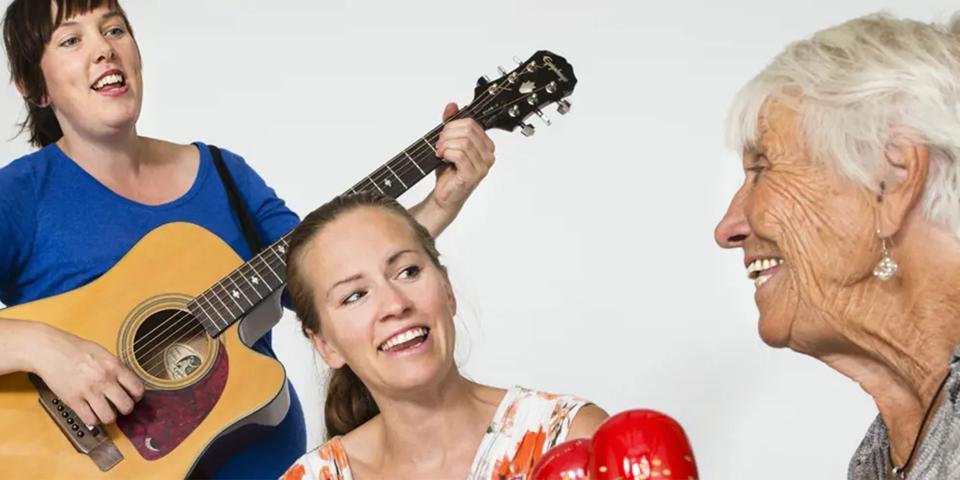 Glada musiker som spelar, glad äldre person i förgrunden.