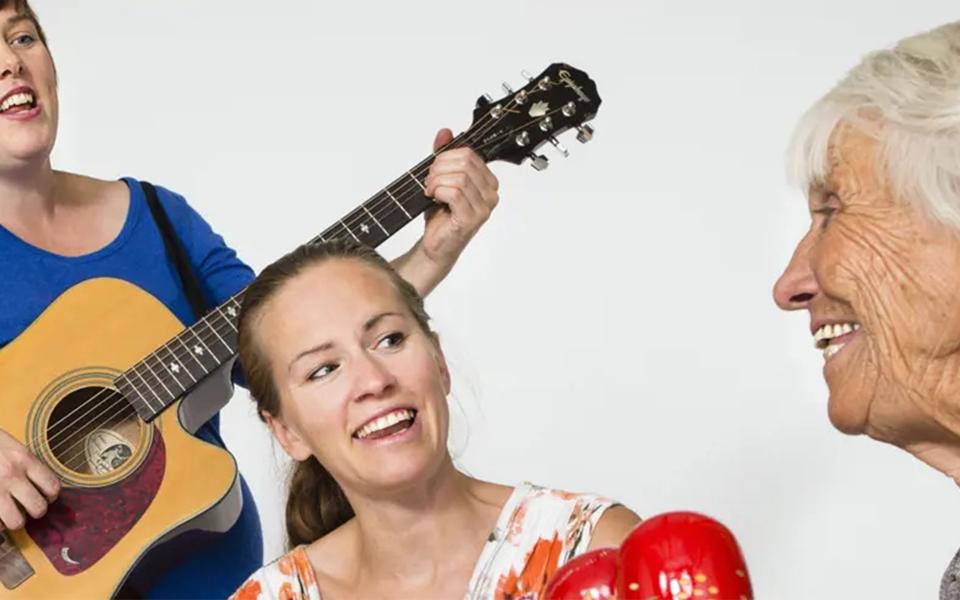 Glada musiker som spelar, glad äldre person i förgrunden.